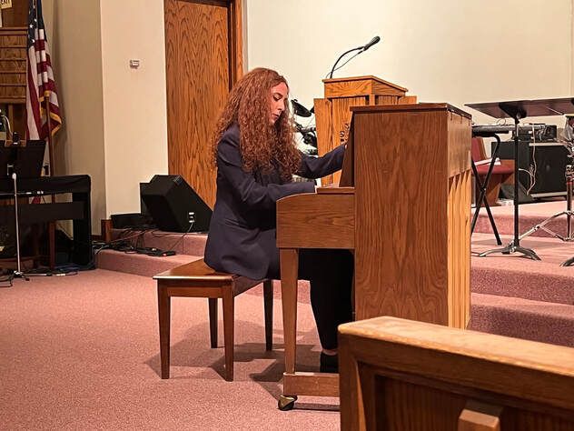 Eva Panagou premieres Connor's solo on an upright piano in a church sanctuary.