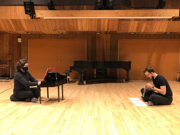 Ariel Magno da Costa and Joshua Heaney perform Connor's duet on small instruments; due to the instrument sizes, they are playing while seated on the floor.