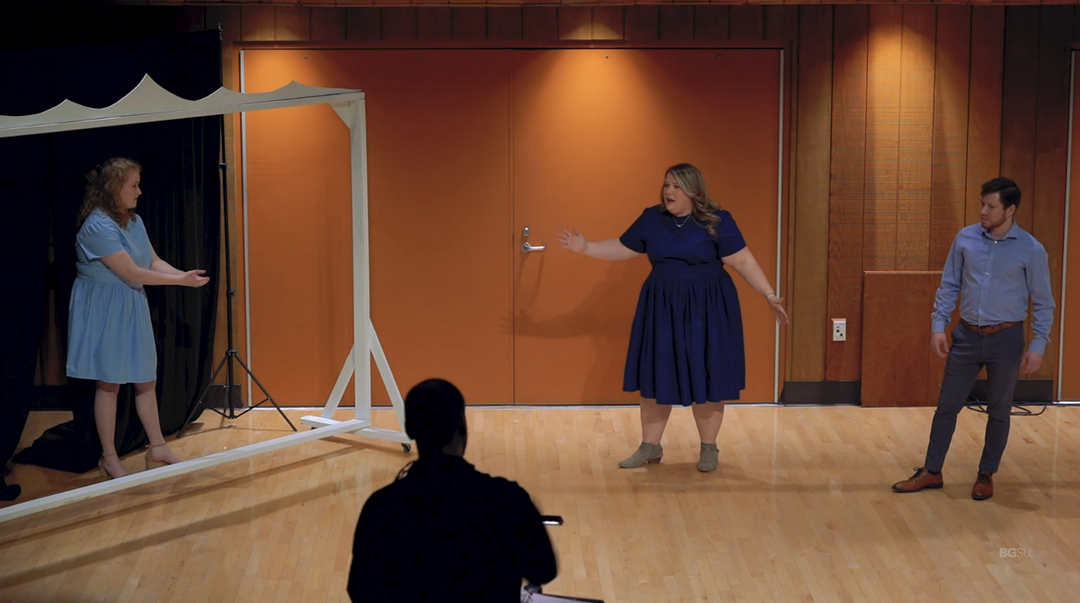 Connor conducts a scene from his chamber opera. Onstage are the three characters, one in a giant frame.